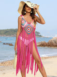 A model wearing a tan hat, white two piece swimsuit, Hot Pink Fringe Spaghetti Strap Cover-Up Dress, and a tan handbag on the oceanfront of the beach