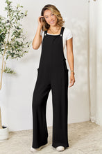 Model styled in Black Cyrella Muse Overalls with heels and statement earrings.