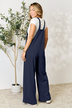 Back view of model in Dark Navy Cyrella Muse Overalls with wide straps detail.
