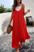 a model posing on a balcony wearing a deep red Backless Maxi Cami Dress with Pockets  paired with jewelry, a woven handbag, and clear heels