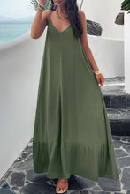 a model posing on a balcony wearing a matcha green Backless Maxi Cami Dress with Pockets  paired with jewelry, and clear heels