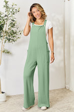 Front view of model in Cyrella Muse Wide-Leg Overalls in soft Gum Leaf color.