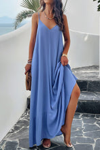 a model posing on a balcony wearing a sky blue Backless Maxi Cami Dress with Pockets  paired with jewelry, a woven handbag, and clear heels