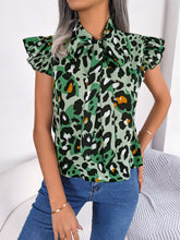 Model styled in a green leopard print cap sleeve blouse with adjustable tie-neck, tucked into tailored trousers.