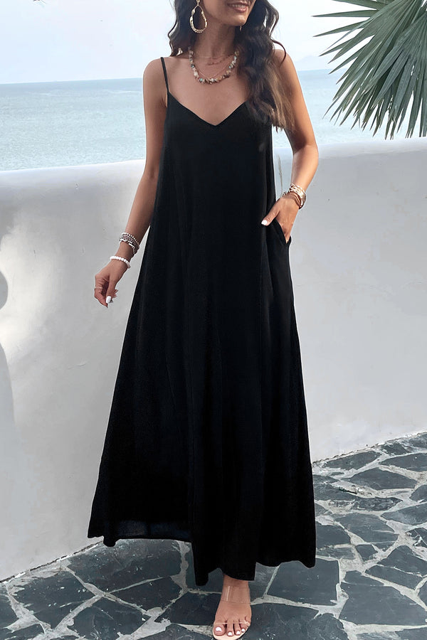 a model posing on a balcony wearing a black Backless Maxi Cami Dress with Pockets  paired with jewelry and clear heels