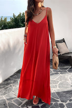 a model posing on a balcony wearing a deep red Backless Maxi Cami Dress with Pockets  paired with jewelry, a woven handbag, and clear heels
