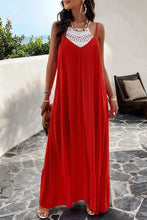 a model posing on a balcony wearing a deep red Backless Maxi Cami Dress with Pockets  paired with jewelry, a woven handbag, and clear heels
