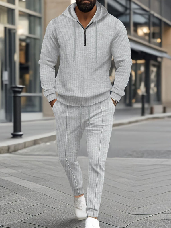 A man hanging out in Atlanta wearing the Gray Tavvion TerrainFlex Waffle-Knit Half Zipper Hoodie and Pants Set  paired with white sneakers.