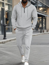 A man hanging out in Atlanta wearing the Gray Tavvion TerrainFlex Waffle-Knit Half Zipper Hoodie and Pants Set  paired with white sneakers.