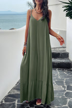 a model posing on a balcony wearing a  matcha green Backless Maxi Cami Dress with Pockets  paired with jewelry, and clear heels