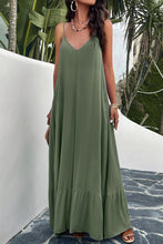 a model posing on a balcony wearing a matcha green Backless Maxi Cami Dress with Pockets  paired with jewelry, a woven handbag, and clear heels 