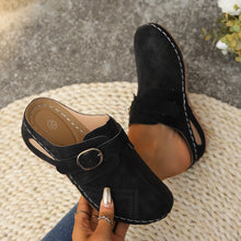 A model showcasing the front a pair of black Suede Round Toe Wedge Sandals with ripped blue jeans.