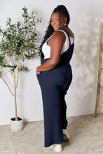 Back view of model in Dark Navy Cyrella Muse Overalls with wide straps detail.