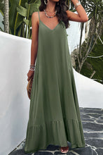 a model posing on a balcony wearing a matcha green Backless Maxi Cami Dress with Pockets  paired with jewelry, a woven handbag, and clear heels
