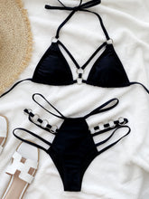 Front flat lay of black cutout halter neck bikini set with gold O-ring connectors and adjustable straps