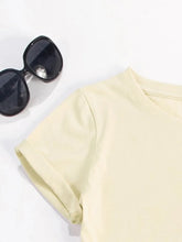 Close-up of CaliVista Tee’s shoulder seams and clean stitching on soft tan fabric styled with sun glasses.