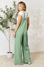 Back view of model in Gum Leaf Cyrella Muse Overalls, highlighting adjustable straps.