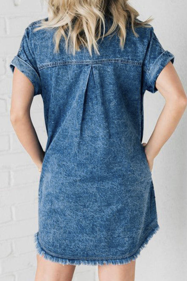 Woman showcasing a back view of  Oressina medium blue Pocket and Raw Denim Dress hightlighting short cuffed cap sleeves. 
