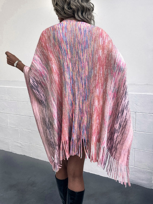 Back view of model wearing a carnation pink Heathered Fringe Hem Poncho, showcasing the soft heathered texture, multicolor contrast accents, and pom pom fringe along the hem.