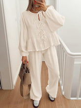 Model walking through condo hall in BellaraNova cream set with sneakers and camel shoulder bag