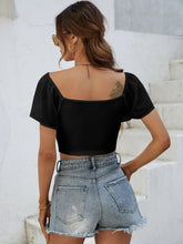 Back view of Glowflutter Crop Top showing soft fabric and flutter sleeve flow, worn by model in black.