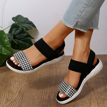 Model wearing PU Leather Open Toe Low Heel Sandals in black houndstooth with legs crossed
