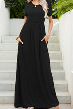Woman posing in front of a tropical white staircase wearing the black Blissurella Round Neck Short Sleeve  Maxi Tee Dress styled with jewelry and open-toe heels.