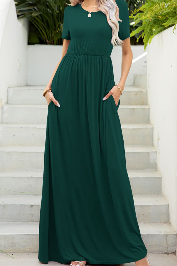Woman posing in front of a white staircase at a masion in the cozy forest green Blissurella Short Sleeve Maxi Dress styled with accessories.