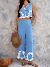 Model in Blue Xyvello set posing against wall holding a straw hat