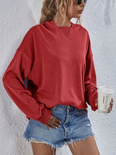 a model wearing a brick red color Zephyra Breeze Dropped Shoulder Hoodie paired with tinted glasses, jewelry, and light blue denim shorts.