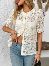 Model wearing the cream lace button-down shirt at an outdoor café, paired with a straw bag and tan sandals for a chic, effortless brunch look.