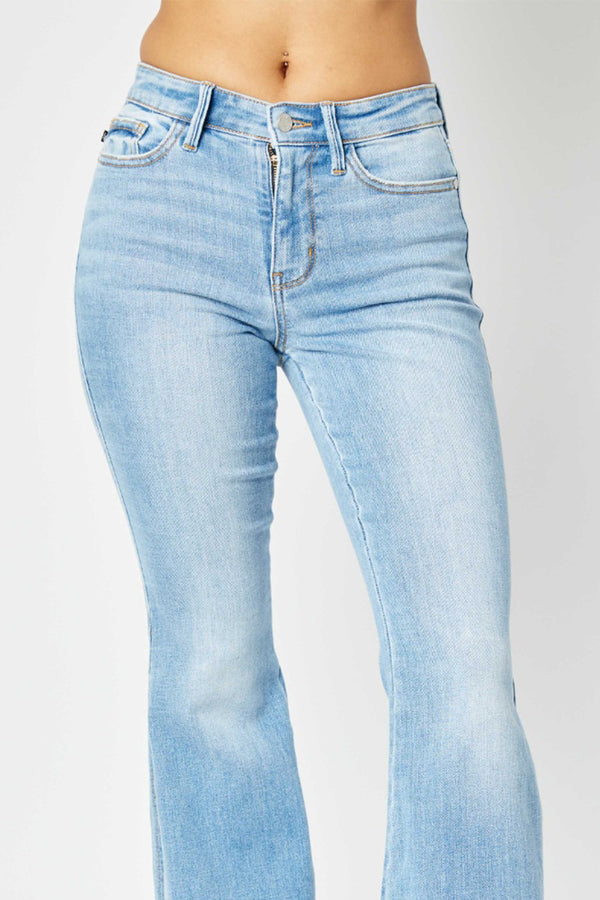 A close-up photo of a female posing from the front wearing the light meduim blue Judy Blue Full Size Mid Rise Raw Hem Slit Flare Stonewashed Jeans.