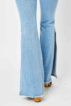 A close-up phote showcasing the bottom side of theA female posing from the front wearing the light meduim blue Judy Blue Full Size Mid Rise Raw Hem Side Slit Flare Stonewashed Jeans  and the fabric quality paired with round open-toe heels.