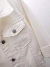 A close up photo of the button detail, pocket, and quality fabric of a white Full Size Cropped Denim Plus Size Jacket.
