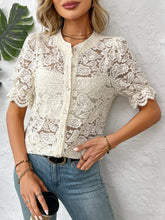 Model wearing a cream lace button-down shirt with faux pearl buttons, styled with light denim jeans and gold hoop earrings.