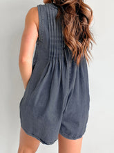 Rear view of dark navy romper reveals clean pleats and tapered waist—casual sophistication styled with a slicked bun.
