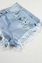 Flat lay side view of light blue distressed denim shorts highlighting raw hem and side seam stitching.