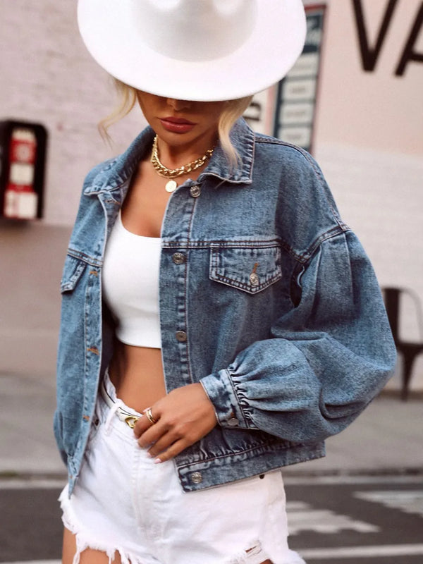 Model wearing a medium-wash denim top with collared neckline, front buttons, and dropped shoulder short sleeves, styled with casual pants.