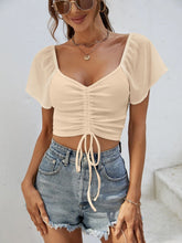 Model in tan Glowflutter Crop Top paired with gold necklace and blazer, styled for casual-chic day look.