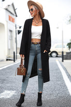 Model styling black Thalora Cascade Cardigan for an evening outing, layered over a dress and boots.