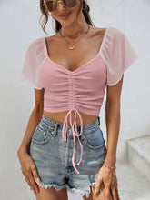 Model in blush pink Glowflutter Crop Top paired with gold necklace and blazer, styled for casual-chic day look.