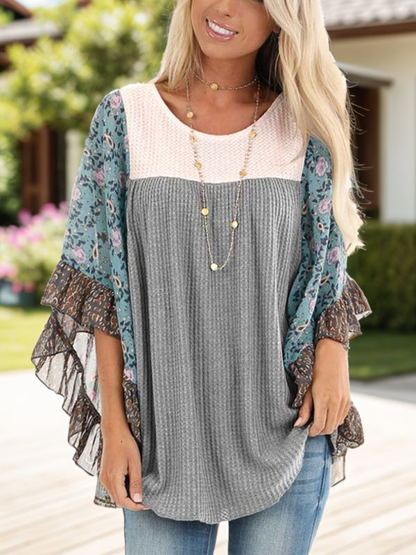 Woman wearing BlossomEase Blouse in gray with floral sleeves and relaxed fit.