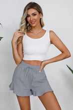 Model in gray shorts enjoying a casual city stroll with sneakers and a tucked-in tee.