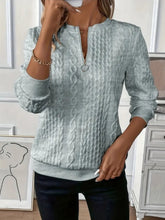 a woman modeling the gray Sunset Coastal Bliss Texture Half Zip Long Sleeve Sweatshirt paired with jewelry, and dark blue denim jeans while taking a selfy photo at the studio