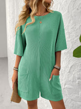 Model in green Breezy Bold Romper front view with hands in pockets.