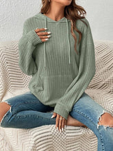 Front view of a woman modeling the Calvessa Hoodie in gum leaf, highlighting the dropped shoulders, soft ribbed fabric, and cozy front pocket.