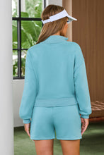 a woman wearing a pastel blue Half-Button Sweatshirt and Shorts Active Set and a white visor