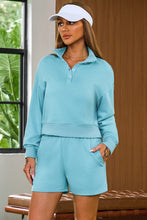 a woman wearing a pastel blue Half-Button Sweatshirt and Shorts Active Set and a white hat