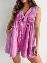 Model in vibrant hot pink romper with tied neckline and rolled sleeves, styled with strappy heels and layered gold necklaces for bold charm.