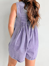 Back of lavender romper shows graceful pleats and feminine cut, complemented by flowing hair and dangling earrings.